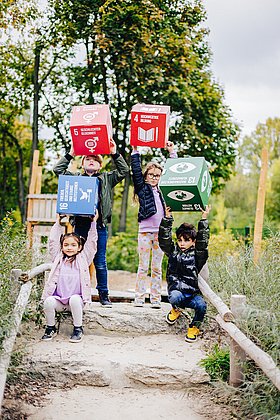 Vier Kinder halten große Würfel mit den Nachhaltigkeitszielen hoch