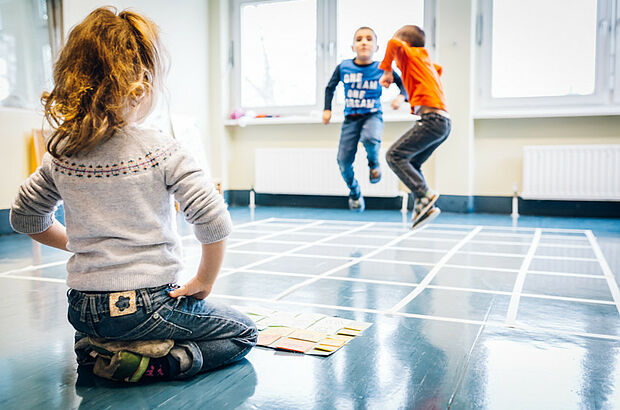 Kinder bewegen sich wie Roboter über ein Quadratfeld.