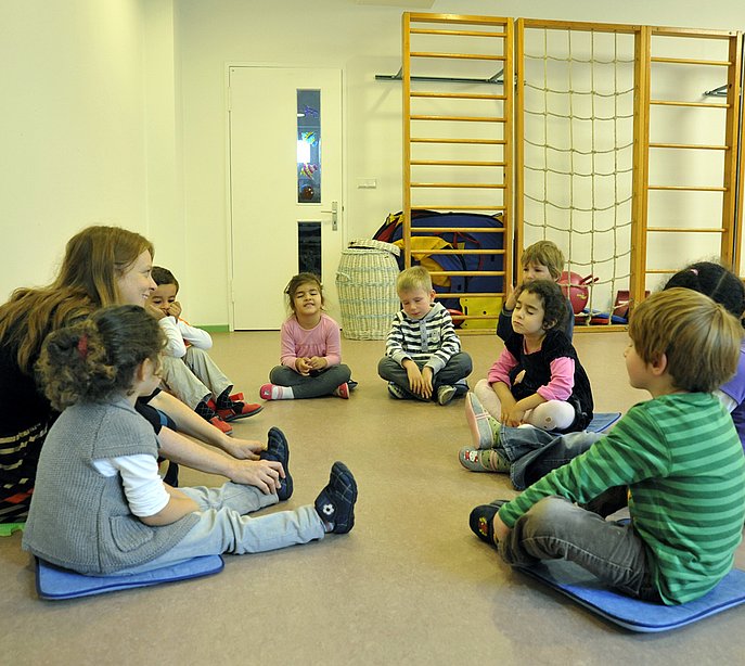 Kinder sitzen mit geschlossenen Augen im Kreis.