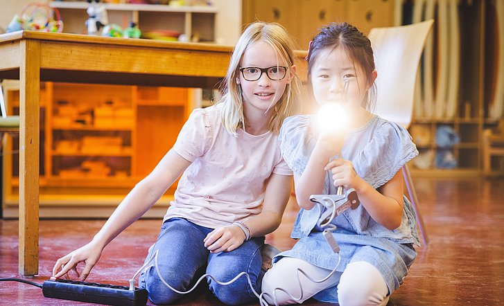 Kinder leuchten mit Taschenlampe in die Kamera
