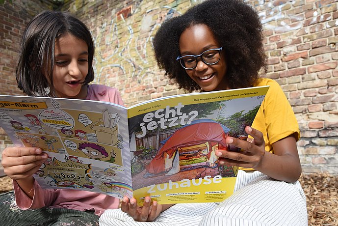 Zwei Mädchen lesen zusammen das Kindermagazin "echt jetzt?".