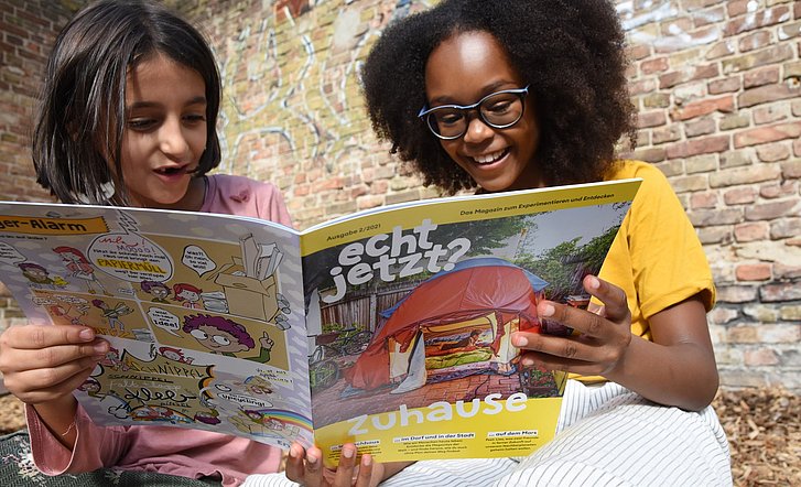 Zwei Mädchen lesen zusammen das Kindermagazin "echt jetzt?".