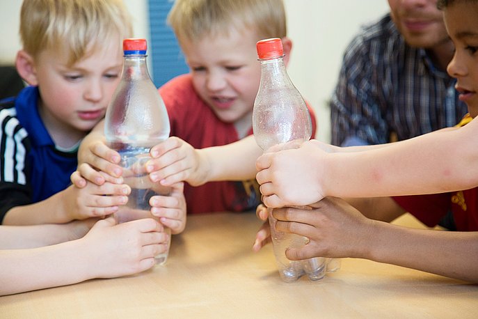 Jungen drücken Plastikflaschen zusammen