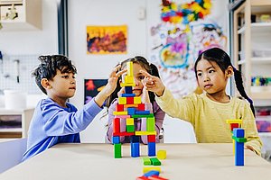 Kinder bauen einen Turm aus bunten Bauklötzen