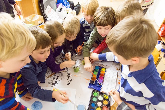 Mehrere Kinder malen gemeinsam mit Wasserfarben