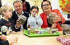 Bildungsministerin Hubig betrachtet mit Michael Fritz, Vorstandsvorsitzendem der Stiftung "Haus der kleinen Forscher" und Mainzer Kita-Kindern Regenwürmer im Glas.