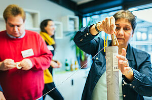 Eine Frau befestigt eine Schnur mit Wäscheklammern an einem Rohr