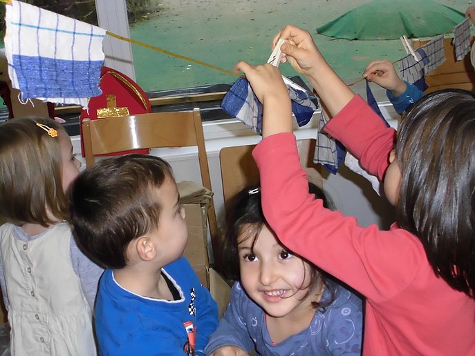 Kinder hängen Stofftücher an eine Wäscheleine