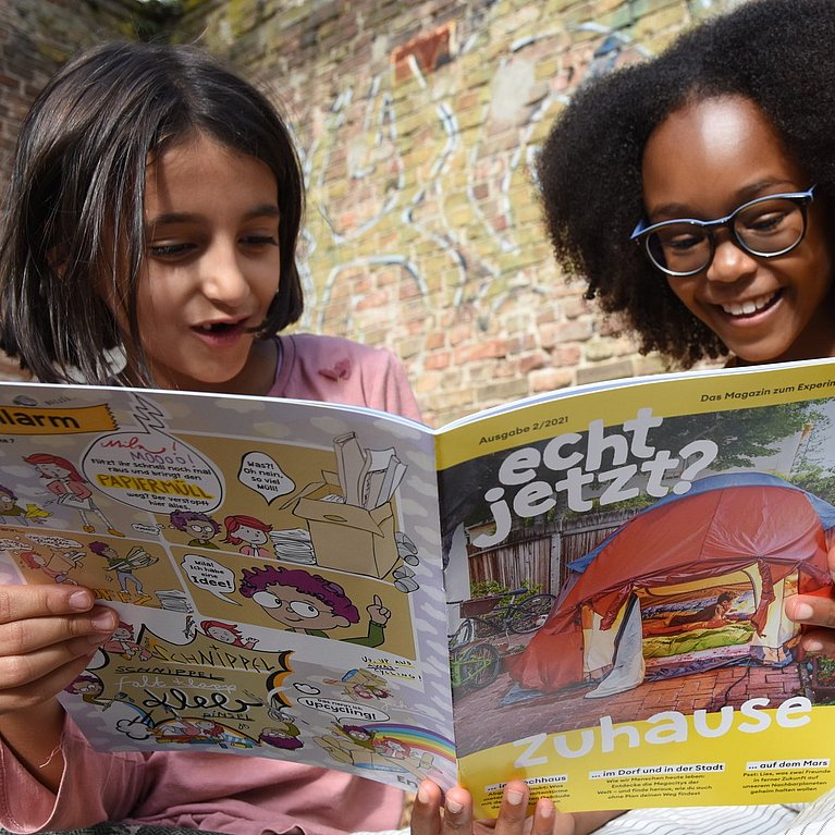 Zwei Mädchen halten das Grundschul-Magazin "echt?" in den Händen.