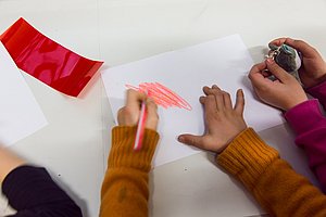 Kinder malen Kritzeleien auf ein weißes Blatt Papier