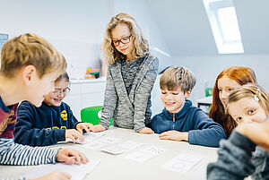 Kinder stehen um einen Tisch und legen Binärcodes mit Punktkarten