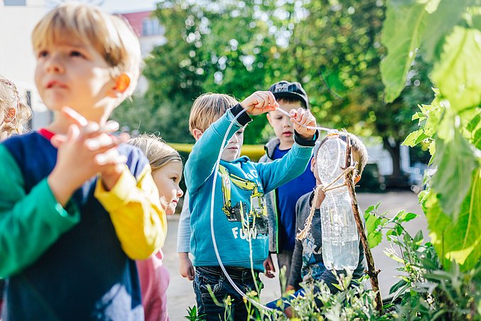 Kita-Kinder bauen ein Bewässerungssystem für Pflanzen aus leeren Plastikflaschen.