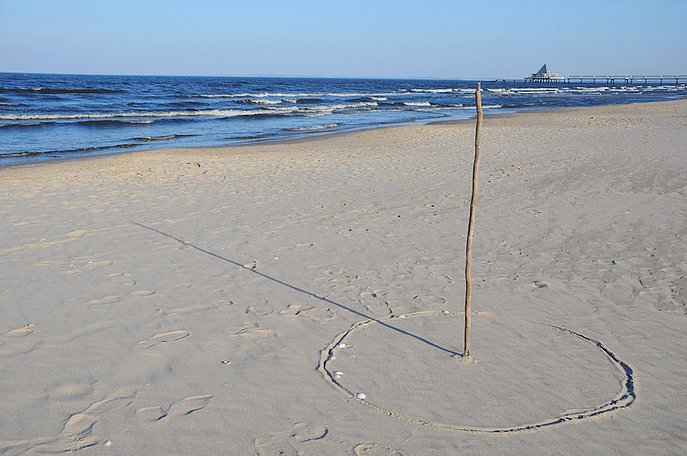 Ein Stock ist am Strand in den Sand gesteckt und dient so als Sonnenuhr.
