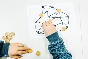 Children's hands distribute wooden tokens on a network picture