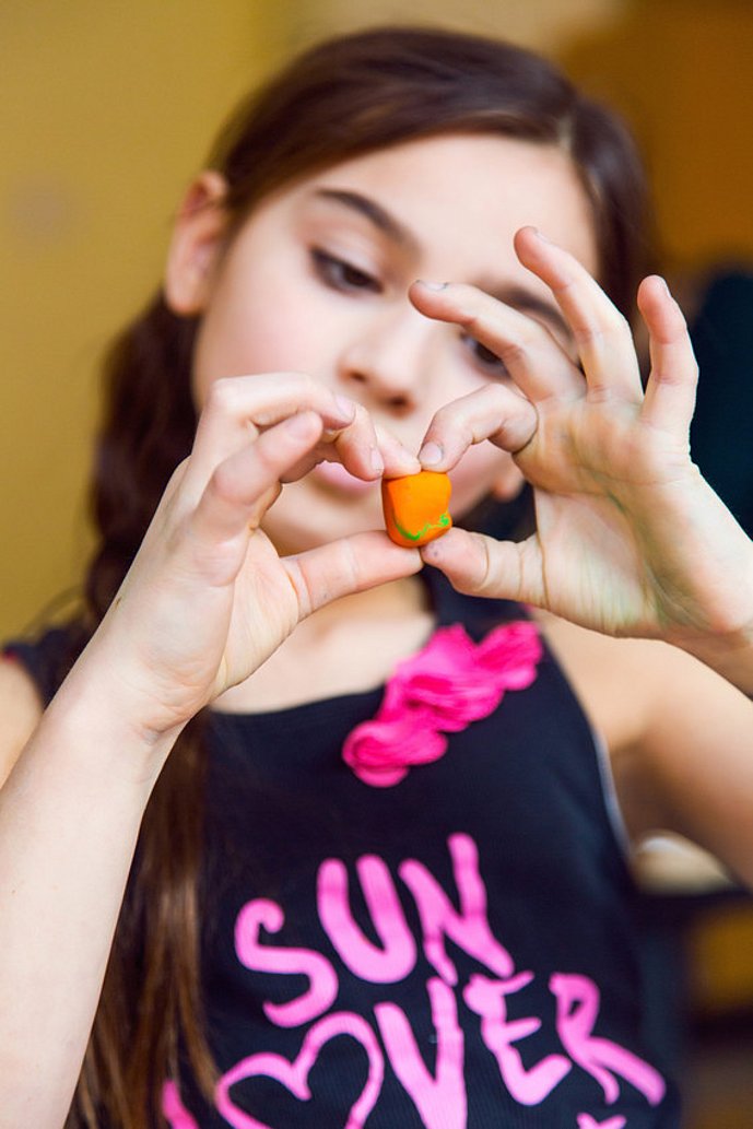 Mädchen hält kleinen Kneteklumpen zwischen zwei Fingern