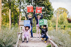 Kinder halten Würfel hoch, die vier der 17 globalen Nachhaltigkeitsziele zeigen.